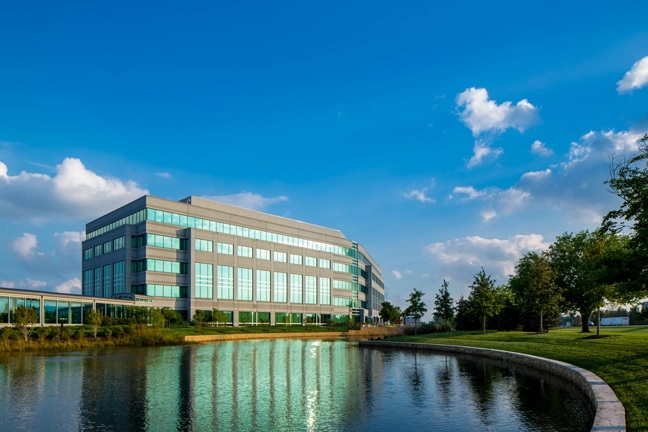 a pond in the foreground with a multi-story office building in the background